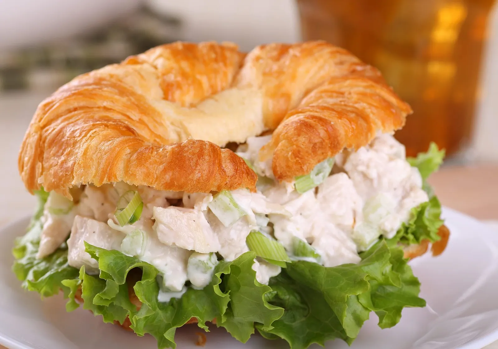 A croissant filled with chunk chicken salad on lettuce
